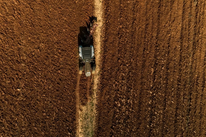 Aerial drone shot of a farmer in tractor seeding, sowing agricultural crops at field in the fertile farm fields of Kilkis in North Greece