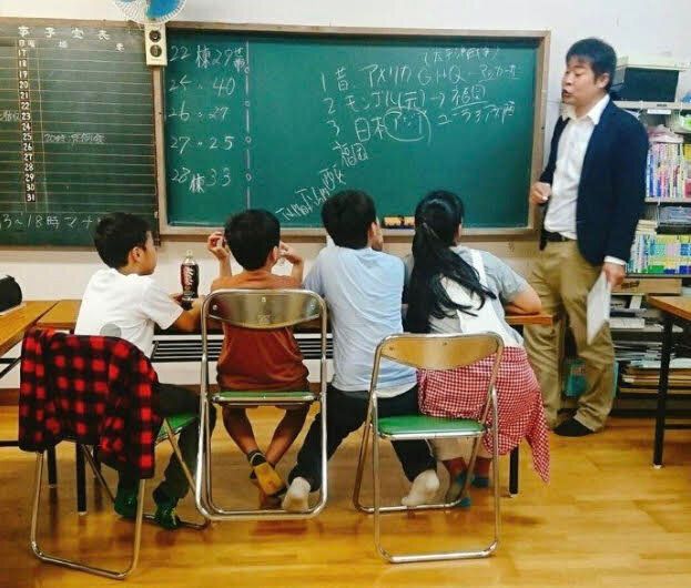 学習支援教室で子どもたちに指導する田口吾郎さん（右）