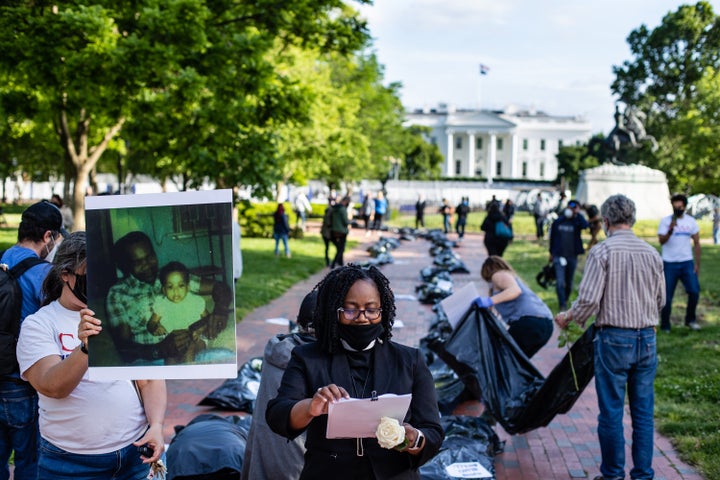 Progressive activists outside the White House in Washington, D.C., lay body bags and photos of loved ones killed by the coron