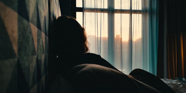 Rear View Of Woman Relaxing On Bed At Home