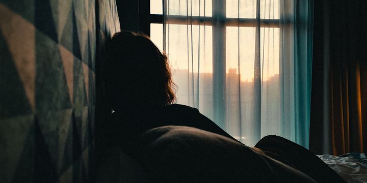 Rear View Of Woman Relaxing On Bed At Home