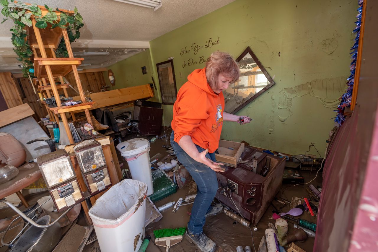 Connie Methner, owner of CJ's Hairstyling, wades through the mud covering the inside of her salon in Sanford, Michigan, on May 21, 2020. 