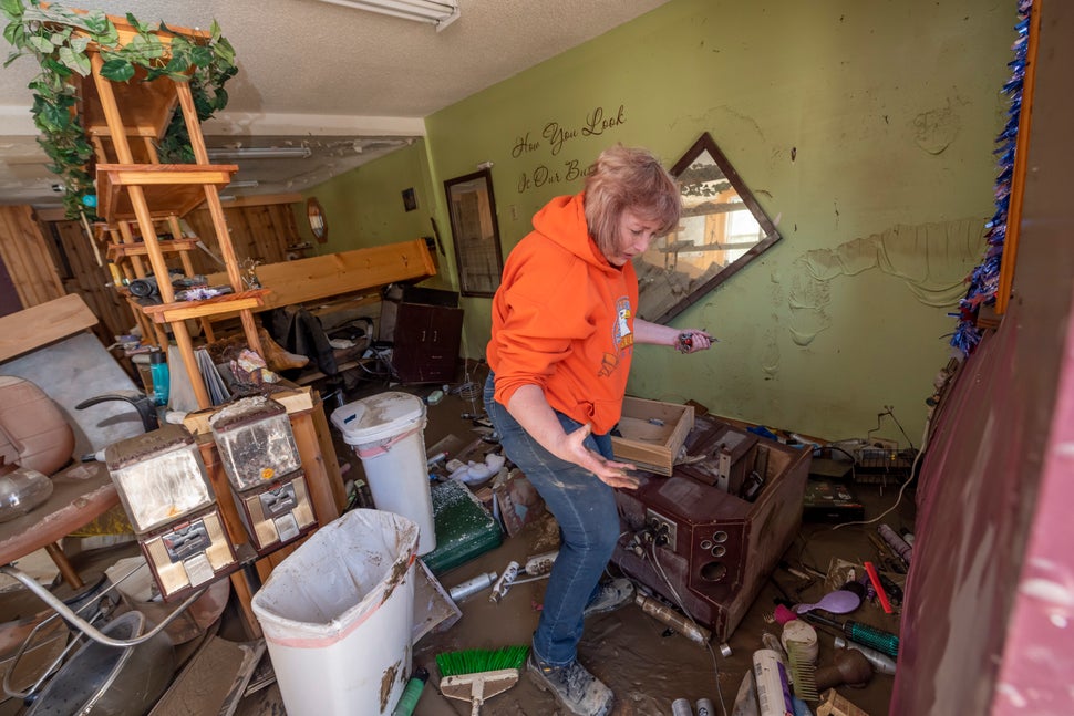 Connie Methner, owner of CJ's Hairstyling, wades through the mud covering the inside of her salon in Sanford, Michigan, on Ma