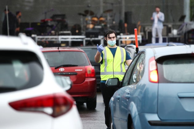 SYDNEY, AUSTRALIA - MAY 21: People are guided into position in their vehicles to watch Casey Donovan perform during a media call to showcase how a drive-in live entertainment venue will operate ahead of its opening in July in the suburb of Tempe on May 21, 2020 in Sydney, Australia. From July visitors will be able to drive to the venue and enjoy music and performances from the safety of their vehicles as restrictions on group sizes continues due to the COVID-19 pandemic. (Photo by Cameron Spencer/Getty Images)