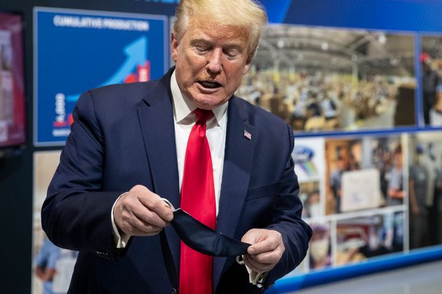 El presidente Donald Trump sostiene una mascarilla mientras habla durante una visita a la Planta de Componentes...