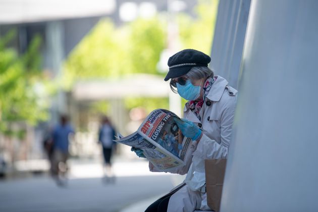 Μάσκα και γάντια για προστασία και ανάγνωση εφημερίδας για τα νεότερα από το μέτωπο του κορονοϊού (Νέα Υόρκη)