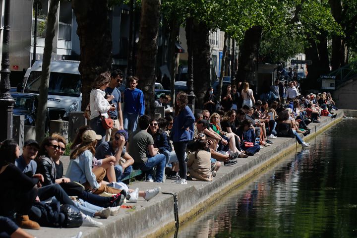 People sit on a bank of the Canal Saint-Martin in Paris, on May 16, 2020, on the first weekend after France eased lockdown measures.