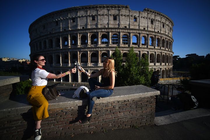 Young women share an aperitif drink by the Colosseum in Rome on May 21, 2020, after the country eases its two-month lockdown.