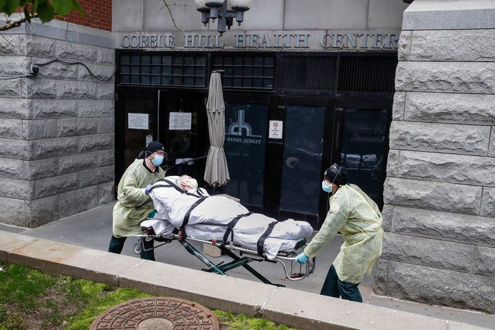 FILE - In this Friday, April 17, 2020 file photo, a patient is wheeled out of the Cobble Hill Health Center by emergency medi