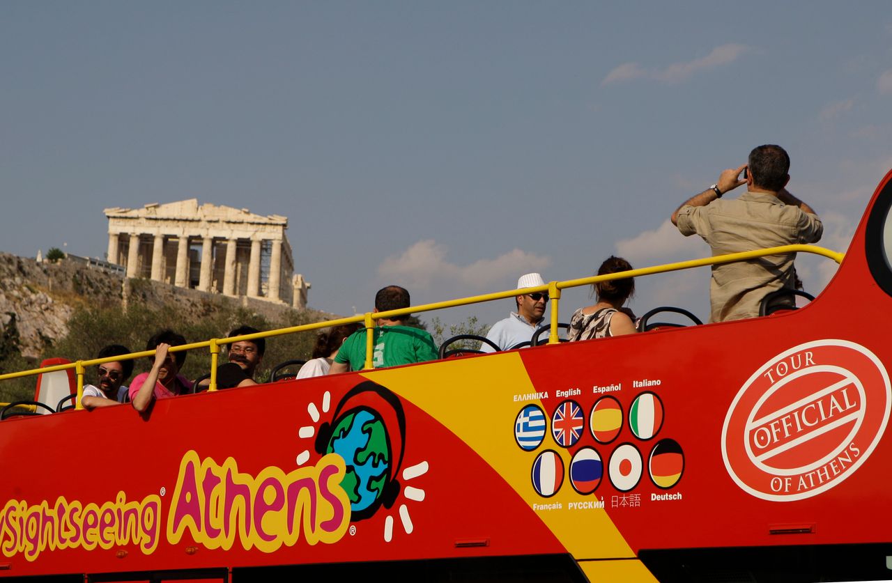 In this photo taken on Wednesday, June 9, 2010 tourists take photos of the ancient Parthenon temple on the Acropolis from an open-topped bus in Athens. Officials say Greece's vital tourism industry is expected to suffer a 10 percent fall in bookings this year compared to 2009, but mass cancellations that followed riots in Athens last month have stopped and the long-term outlook is good. Tourism contributes to some 17 percent of Greece's annual economic output, and creates an estimated one in five jobs. (AP Photo/Petros Giannakouris)
