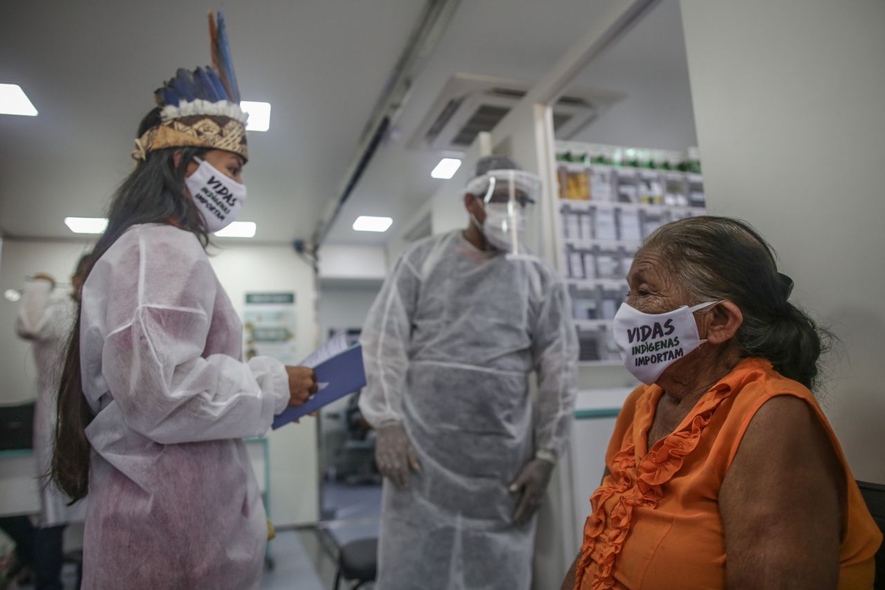 Ιθαγενείς νοσοκόμα βοηθά ηλικιωμένή γυναίκα να εξεταστεί για κορονοϊό (21 Μαϊου)