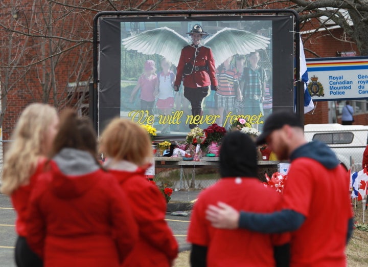 Mourners, asked to wear red, are seen near a mural dedicated to slain RCMP Const. Heidi Stevenson, during a province-wide, two-minutes of silence for the 22 victims of last weekend's shooting rampage, in front of the RCMP detachment in Cole Harbour, N.S. on April 24, 2020.