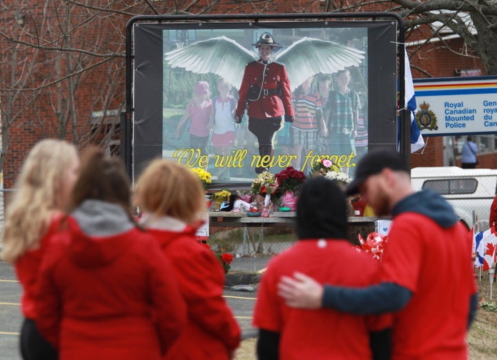 Mourners, asked to wear red, are seen near a mural dedicated to slain RCMP Const. Heidi Stevenson, during a province-wide, two-minutes of silence for the 22 victims of last weekend's shooting rampage, in front of the RCMP detachment in Cole Harbour, N.S. on April 24, 2020. 