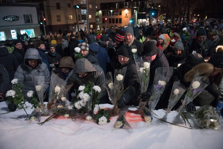 People lay flowers in memory of the victims near the Islamic Cultural Centre in Quebec City on Jan. 29, 2018. 