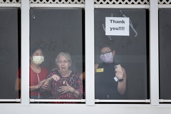 Residents and staff wave to family and friends who came out to show support of those in the McKenzie Towne long term care centre in Calgary on April 2, 2020.