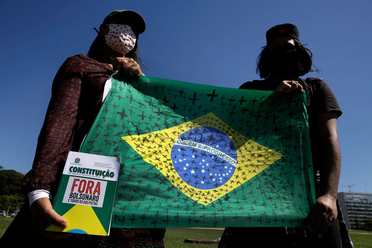 Demonstrators hold a national flag marked with black crosses during a protest demanding Brazilian president Jair Bolsonaro be impeached.