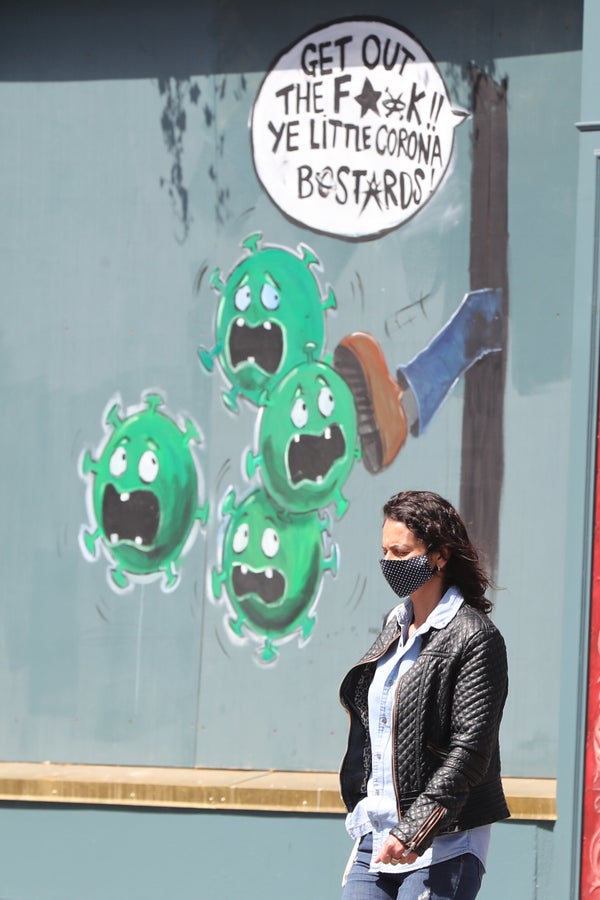EDITORS NOTE: LANGUAGE A woman walks past a coronavirus mural outside Devitts Pub on Camden Street, Dublin. (Photo by Niall C