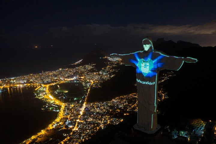 Το Άγαλμα του Χριστού Λυτρωτή (Cristo Redentor στα πορτογαλικά) στην κορυφή του λόφου Κορκοβάντο (Corcovado), πάνω από το Ρίο ντε Τζανέιρο (AP Foto/Leo Correa). Οι αρχές σε μια προσπάθεια ευαισθητοποίησης του πληθυσμού για την αντιμετώπιση της πανδημίας έχουν φωτίσει το άγαλμα με τρόπο τέτοιο που φαίνεται ότι ο Χριστός φορά μάσκα. Τα γράμματα που προβάλλονται επάνω του γράφουν "Η Μάσκα Σώζει".