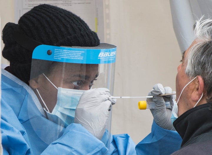 A health-care worker prepares to swab a man at a walk-in COVID-19 test clinic in Montreal on May 10, 2020.