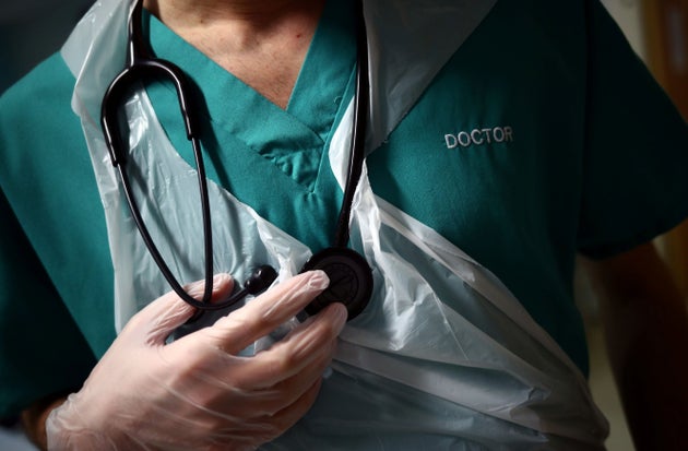 A junior doctor, wearing gloves holds his stethoscope during a patient visit on Ward C22 at the Royal Blackburn Teaching Hospital in Blackburn, north-west England on May 14, 2020, as national health service (NHS) staff in Britain fight the novel coronavirus COVID-19 pandemic. (Photo by HANNAH MCKAY / POOL / AFP) (Photo by HANNAH MCKAY/POOL/AFP via Getty Images)