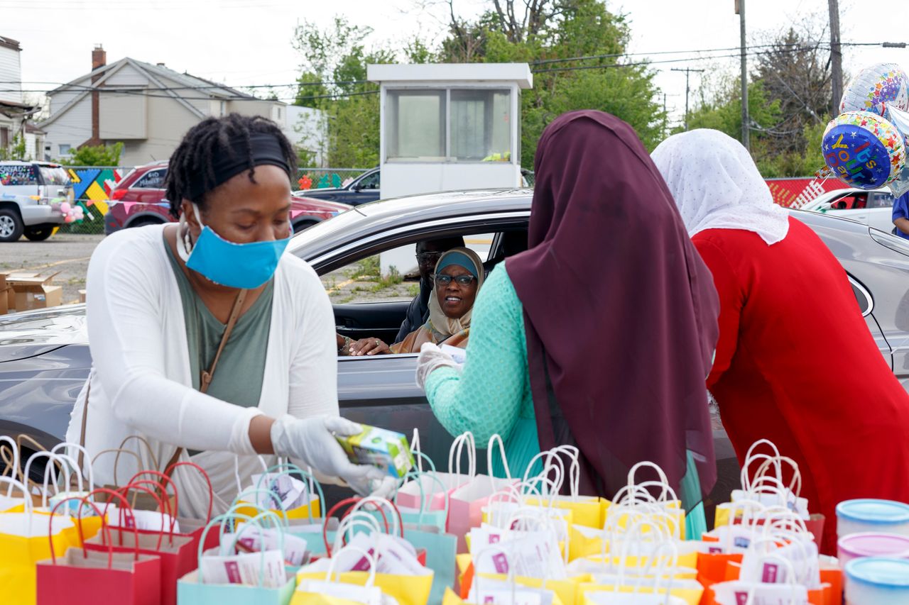 Dedra Allen, left, helps put juice boxes into goodie bags while two other volunteers hand bags to a family before the Woodward Eid Cruise on Sunday, May 24, at the Muslim Center Masjid in Detroit. Eid al-Fitr marks the end of the holy month of Ramadan.