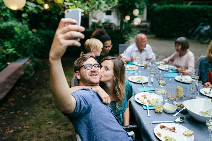 A couple taking a selfie with a smartphone during a barbecue with the family.