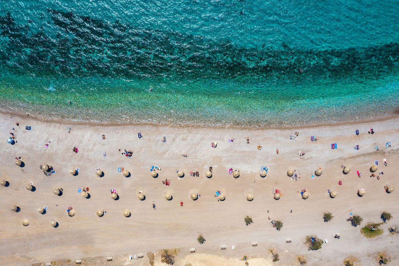 Aerial top down view to the beach of Glyfada district, south Athens Riviera, Greece, with umbrellas set away from each other under Corona social distancing measures