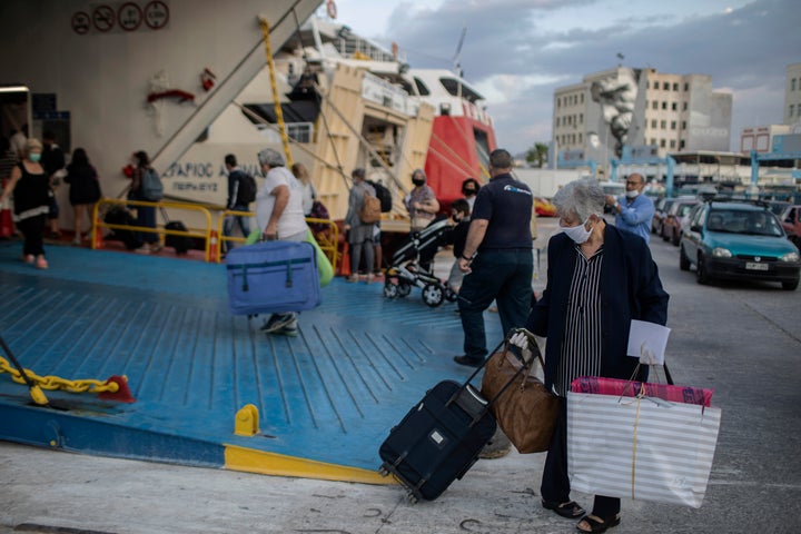 Passengers wearing mask to reduce the spread of the coronavirus board a ferry at the Piraeus port near Athens on Monday, May 25, 2020. Greece restarted Monday regular ferry services to the islands as the country accelerated efforts to salvage its tourism season.(AP Photo/Petros Giannakouris)