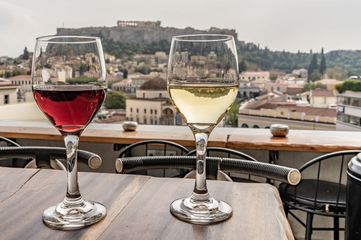 Glasses of wine with a view of the Acropolis in Athens, Greece. Red and white wine. Wide angle close up.