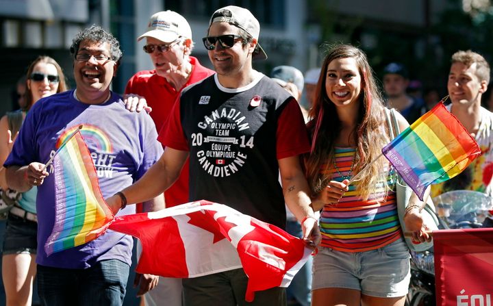 Calgary Mayor Naheed Nenshi marches with Olympians Samuel Edney, centre and Shannon Rempel during Calgary's pride parade on Sept. 1, 2013.