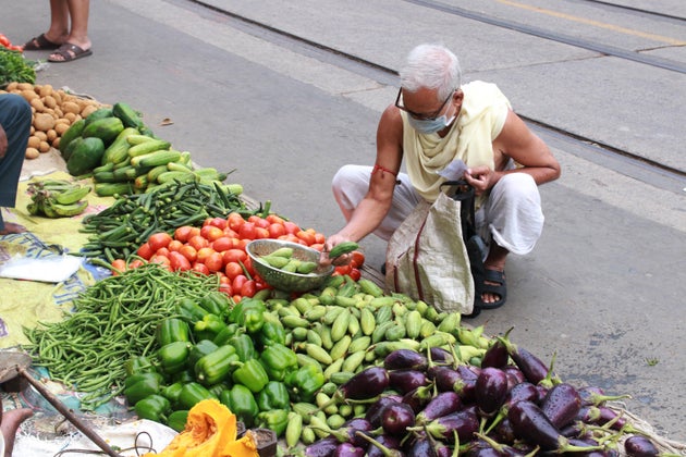 People buy vegetables from a market in Kolkata after the government eased lockdown on May 25,