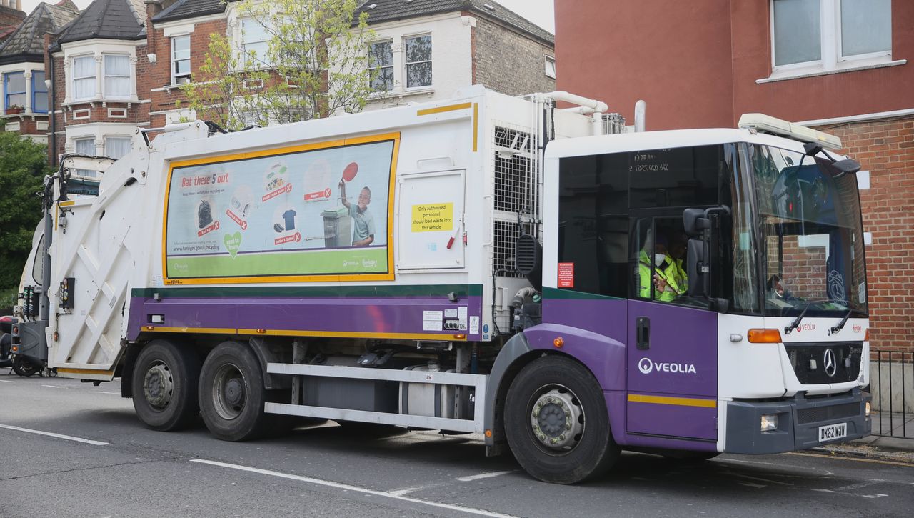 A worker wearing a protective face mask drives a bin lorry in north London