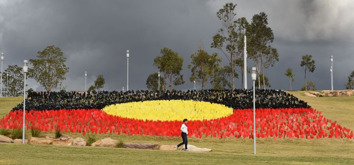 TOPSHOT - A woman passes a huge art installation called 'Sea of Hands' which consists of thousands of hands in the colours of the Aboriginal flag red, yellow, black.Part of National Reconciliation Week 2016, the installation is for Australians to reflect on Australias national identity and the place of Aboriginal and Torres Strait Islander histories and cultures in the nations story. / AFP / William WEST (Photo credit should read WILLIAM WEST/AFP via Getty Images)