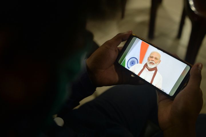 A youth watches Prime Minister Narendra Modi's address to the nation on his mobile phone in Siliguri, West Bengal on 12 May, 2020. 