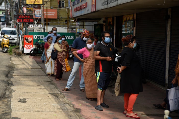 People wearing masks as a precaution against the coronavirus line up outside a government ration shop in Kochi, Kerala, May 20, 2020. 