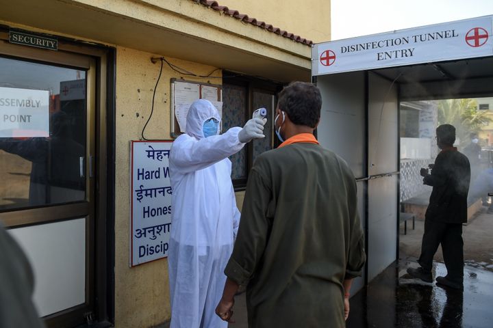 A health worker checks the body temperature of a worker at DH Cube Industries at Vasna Buzarg village, some 40 kms from Ahmedabad on May 14, 2020.