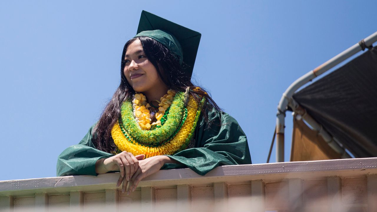Gemalyn Yutob, a Leilehua High School graduate, wears various leis over her graduation gown at her home in Wahiawa, Hawaii, on May 23.
