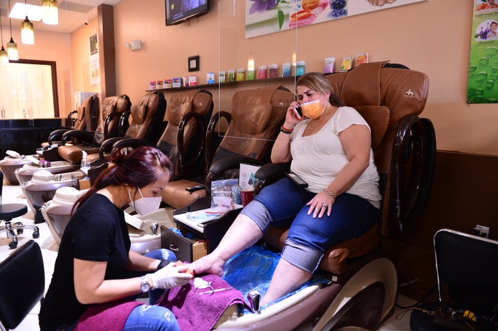 Nail technician Jimmie and her customer wear masks during a pedicure at Nails and Spa salon on May 20, 2020, in Miramar, Florida.