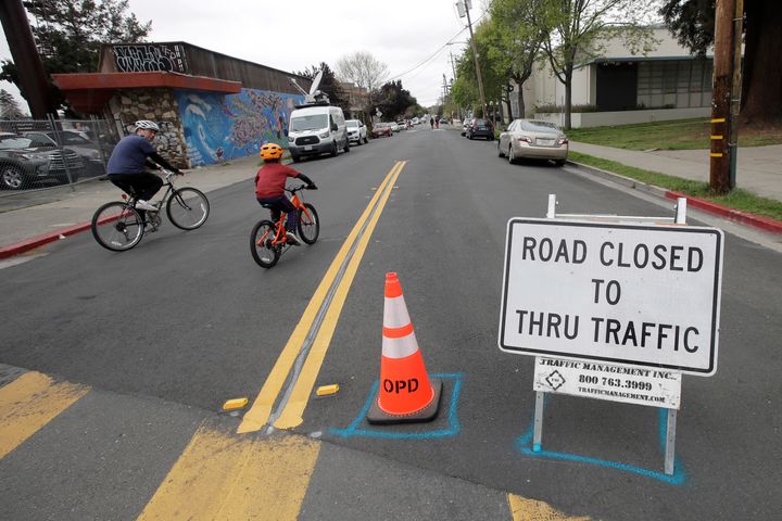 A man and child ride bicycles on a street closed to traffic in Oakland, California, on April 11, 2020. All around the country and the world, bicycles are selling out and officials are trying to take advantage of the growing momentum by expanding bike lanes during the coronavirus pandemic. 