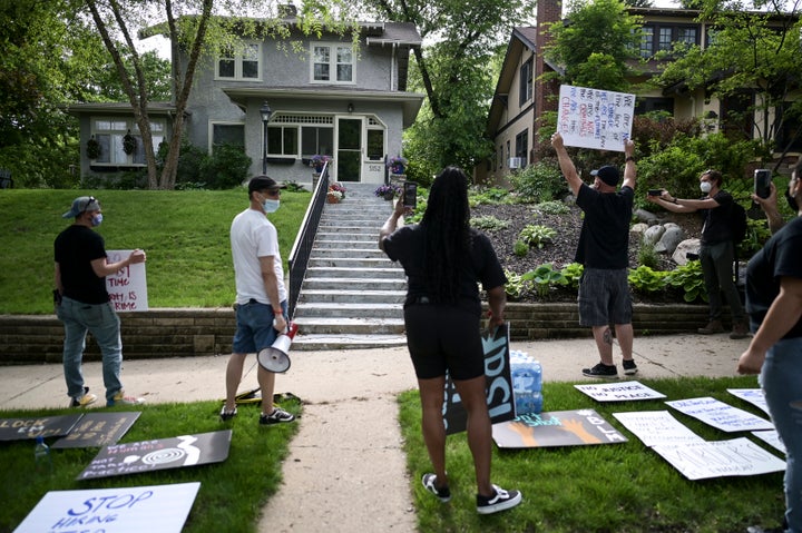 Protesters angered by the death of George Floyd stand Wednesday outside the home of Hennepin County Attorney Mike Freeman in Minneapolis. The mayor of Minneapolis called for criminal charges against the white police officer seen on video kneeling against the neck of a handcuffed Black man who died in police custody.