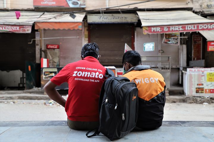 Swiggy and Zomato delivery partners rest near closed restaurants in DLF Phase III, Gurugram on the outskirts of New Delhi on 05 April 2020. 