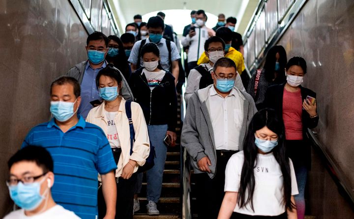 北京の地下鉄駅で、マスクを着けて通勤する人々（中国・北京）