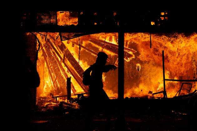 A protester runs in front of the burning 3rd Precinct building of the Minneapolis Police Department, Thursday, May 28, 2020, in Minneapolis.