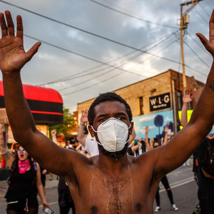 A protester wearing a face mask holds up his hands during a May 27 demonstration outside Minneapolis' 3rd Police Precinct over the police killing of George Floyd.