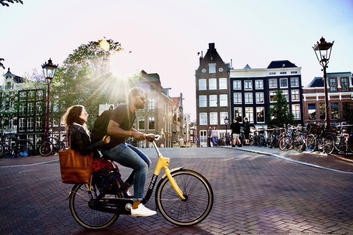 A man rides a bicycle with a woman on the back in Amsterdam. Bikes are part of daily life in the Netherlands.