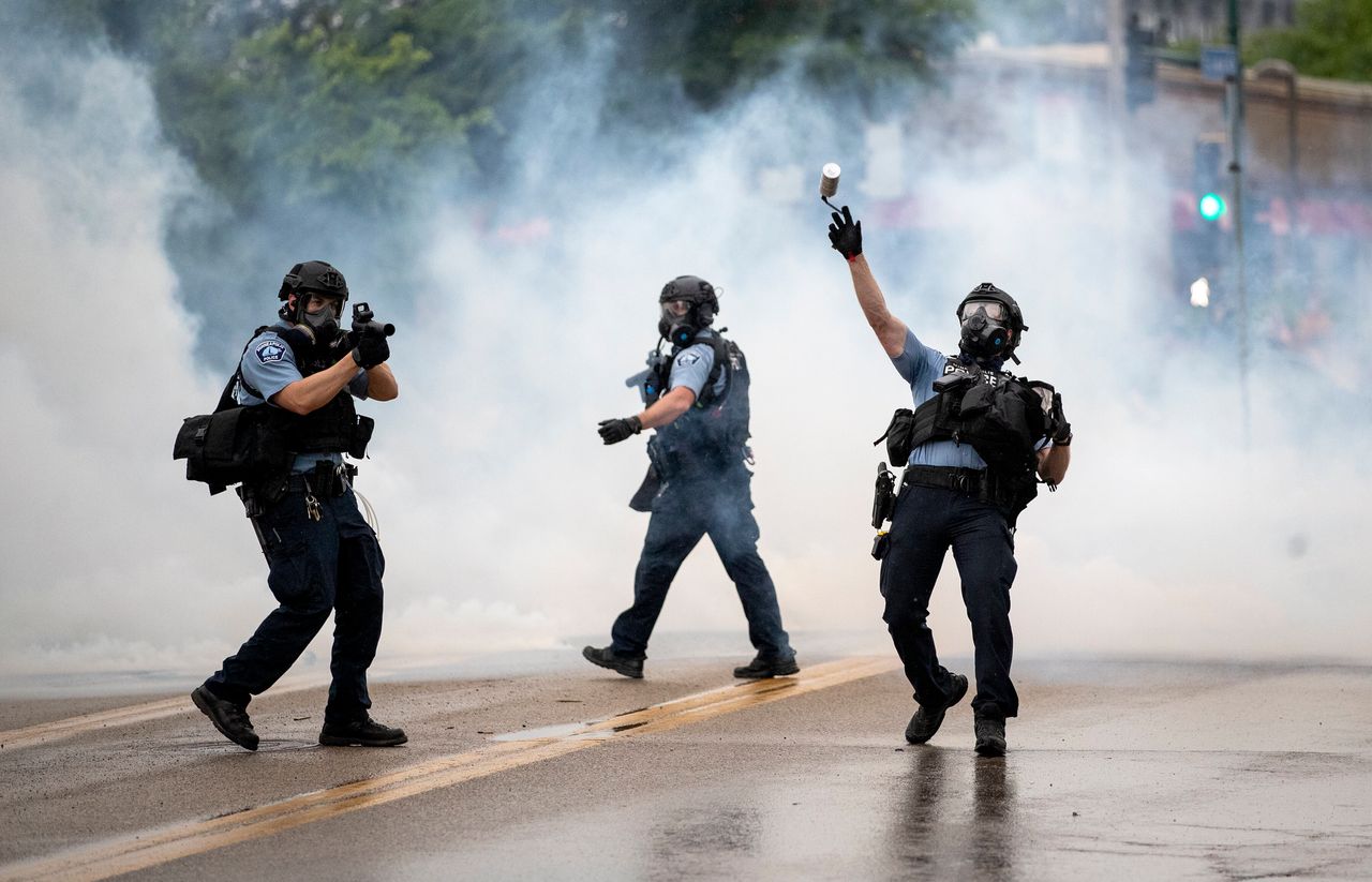 A police officer throws a tear gas canister towards protesters at the Minneapolis 3rd Police Precinct, following a rally for George Floyd on Tuesday, May 26.