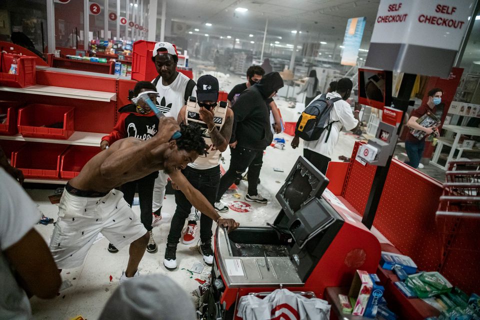 A looter uses a claw hammer as he tries to break in to a cash register at a Target store in Minneapolis.