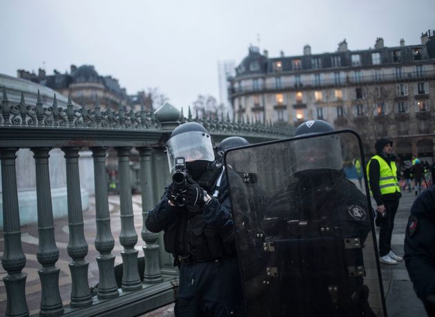 Un policier braque un LBD en direction de la foule durant l'Acte XI des gilets jaunes à Paris,...