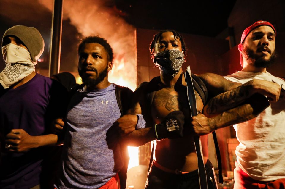 Protestors demonstrate outside of a burning Minneapolis 3rd Police Precinct, Thursday.