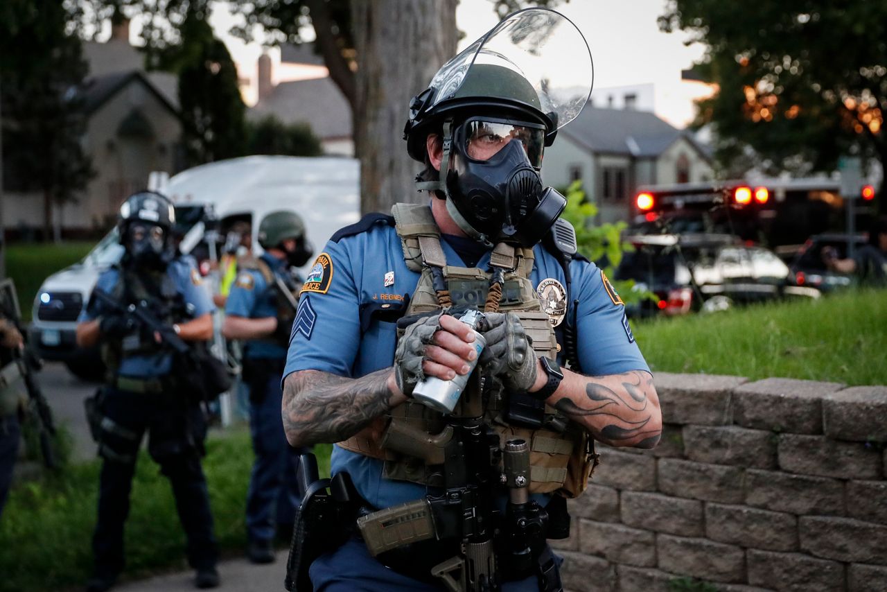 A police officer prepares to throw a tear gas canister towards protestors on Thursday.